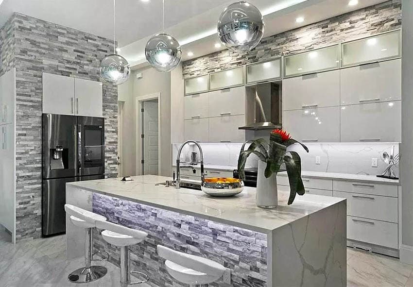 Glam kitchen with white cabinets with under lighting waterfall quartz countertops stacked stone island