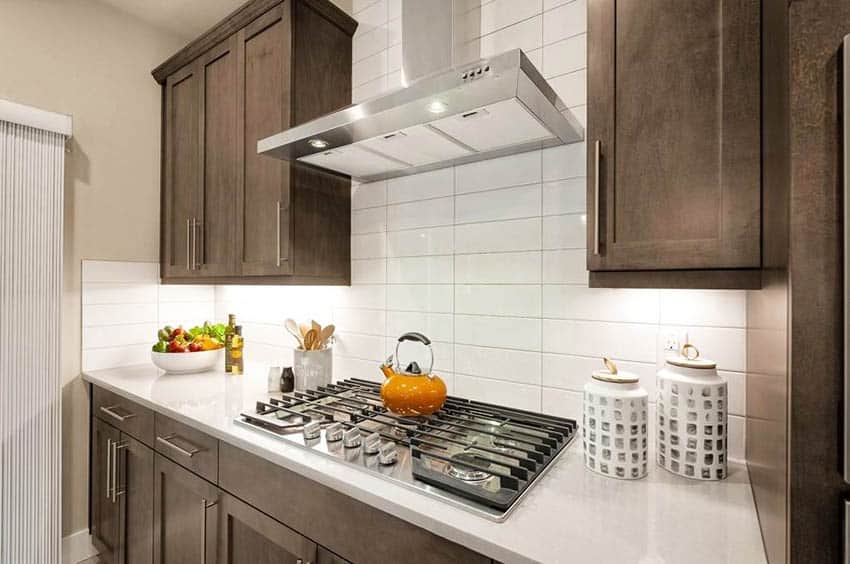 Kitchen with dark wood cabinets with under cabinet lighting white quartz countertops