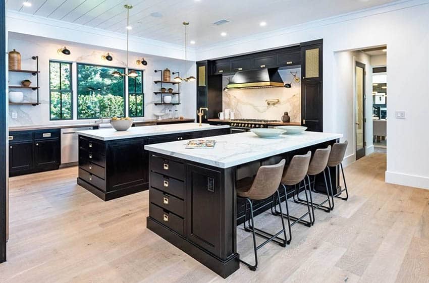 Kitchen with two islands, dark cabinets and marble surface countertops