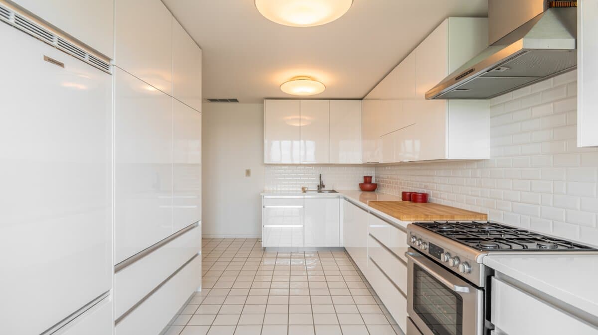 Compact galley kitchen with high-gloss white handleless cabinets and butcher block counters
