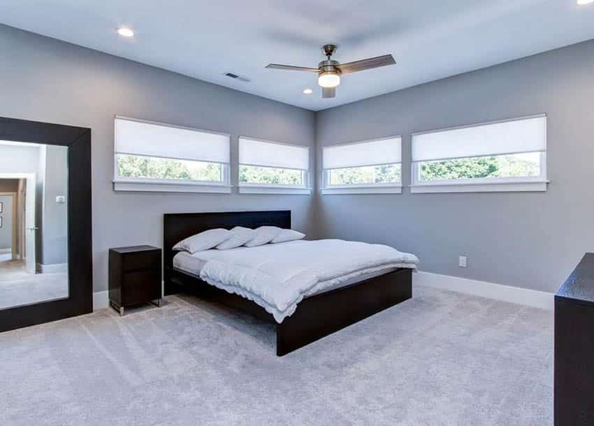 Modern bedroom with bed placement under window white blinds