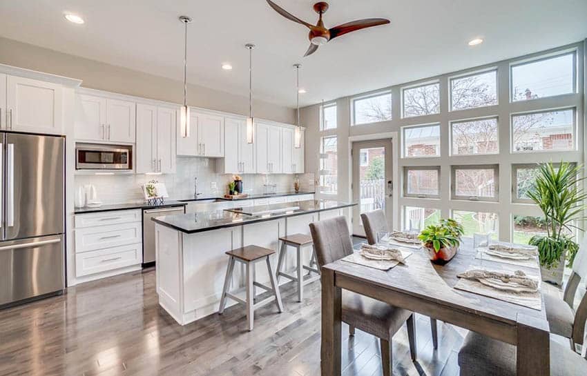 Open concept kitchen with wood staged dining table, white cabinets and polished wood floors