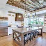Open plan kitchen with large gray quartz island white cabinets wood tray ceiling
