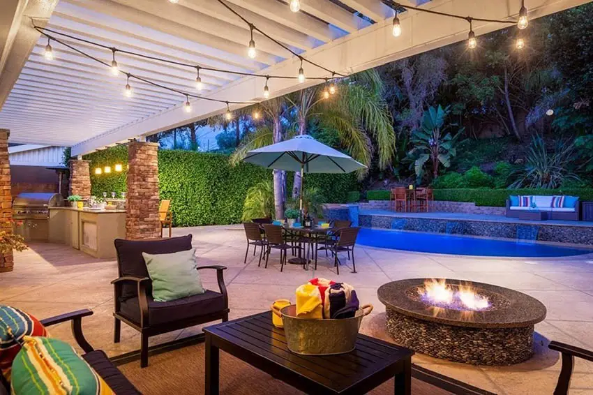 Backyard with granite top fire pit and pool with string lights