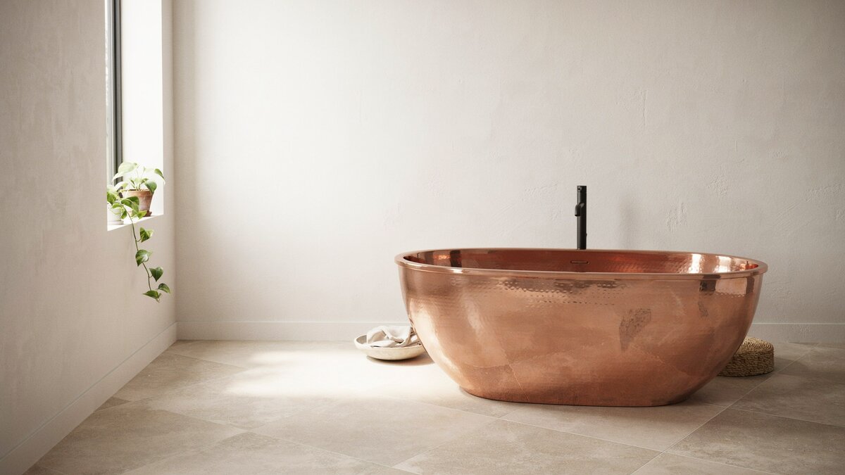 Smooth oval copper tub on pale tile with a slim black floor faucet