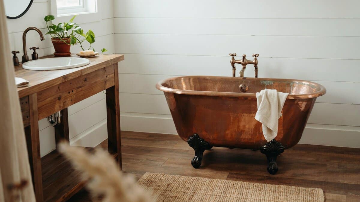 Rustic bathroom with a black footed copper tub over a woven jute rug