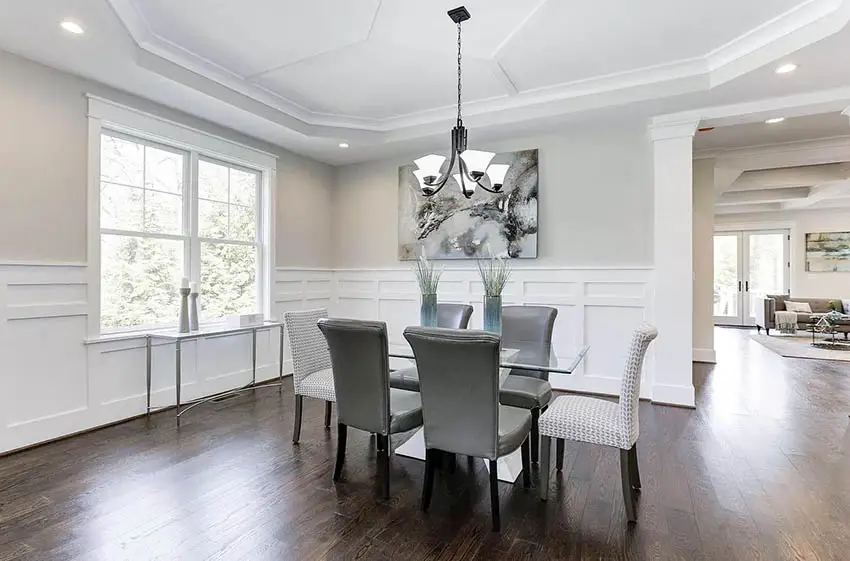 Contemporary dining room with table centerpieces, tray ceiling and white wainscoting