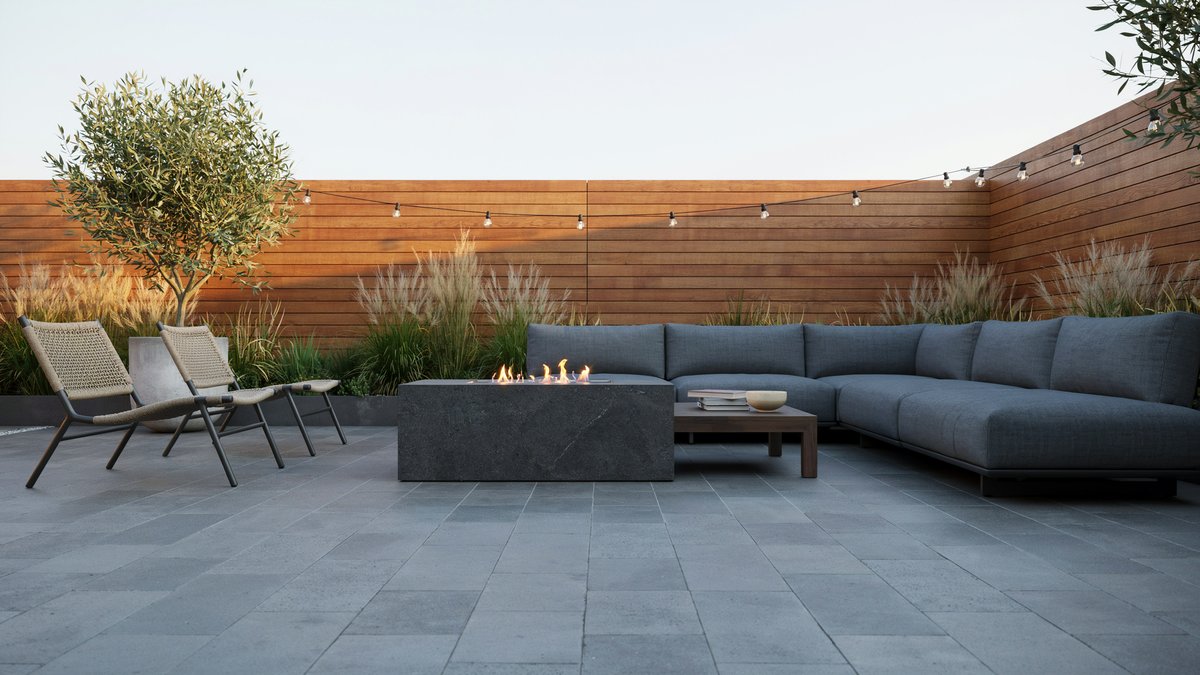 Low charcoal granite fire pit table with gray sectional on porcelain pavers