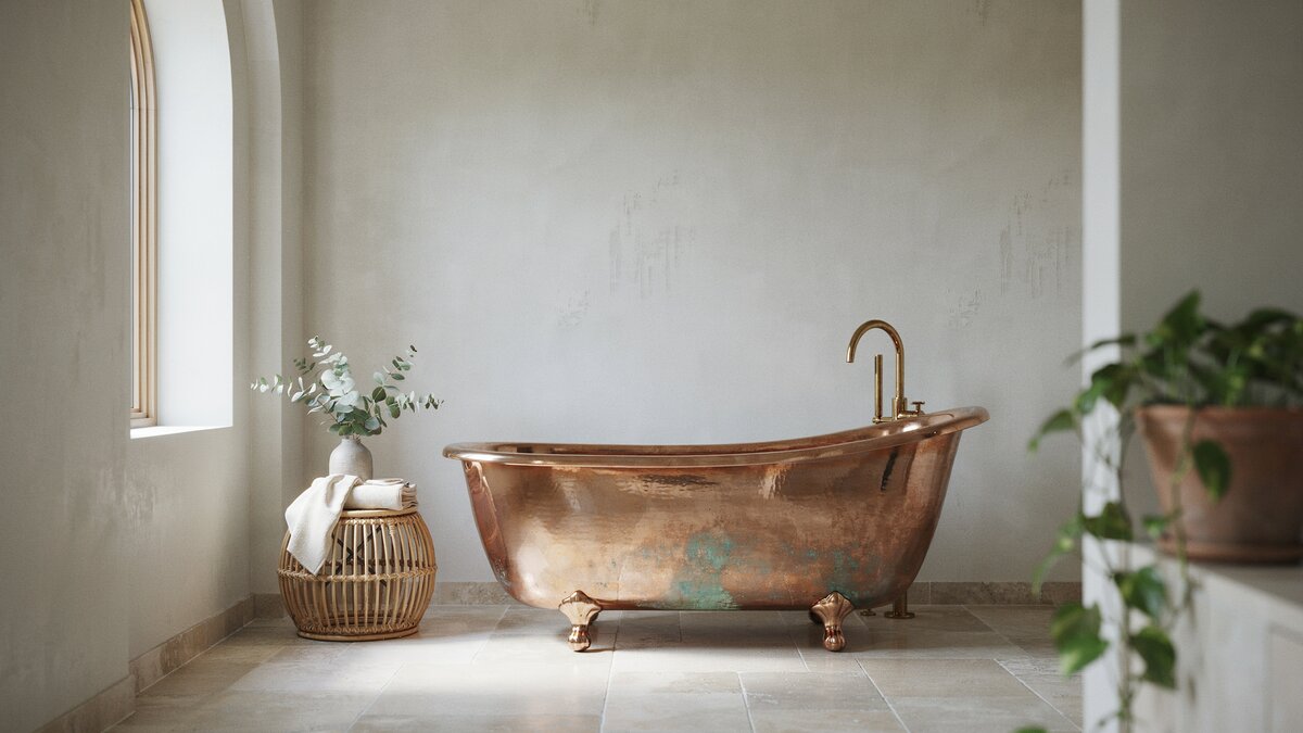 Copper double slipper tub with soft green patina against pale plaster walls