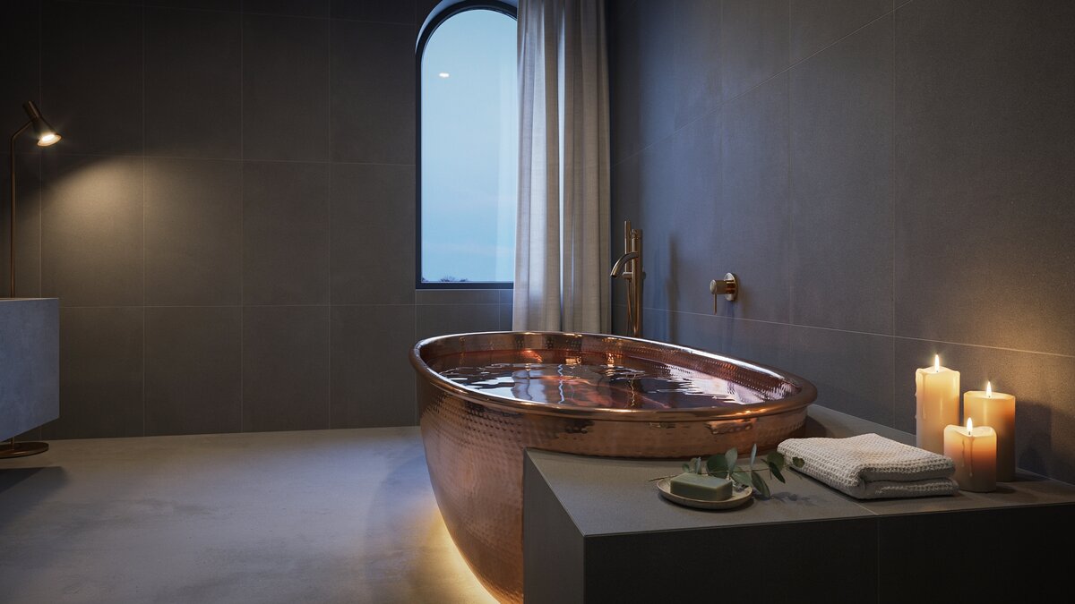 Copper drop in tub framed by a dark tiled surround with lit candles