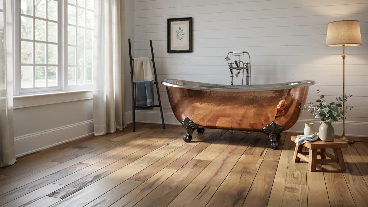 Clawfoot copper tub on wide plank floors with a ladder towel rack nearby