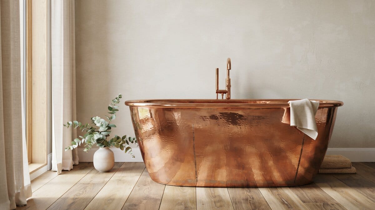 Hand formed copper tub with a rolled rim beside a reclaimed wood vanity