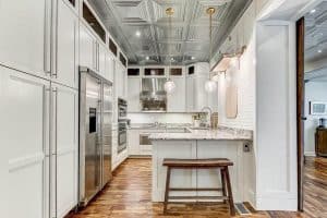High Ceiling Kitchen With White Cabinets Tin Ceiling Tiles Pendant Lighting And Granite Peninsula 300x200 