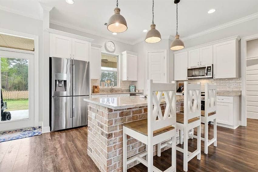 Kitchen with lime washed brick island, white cabinets and wood flooring