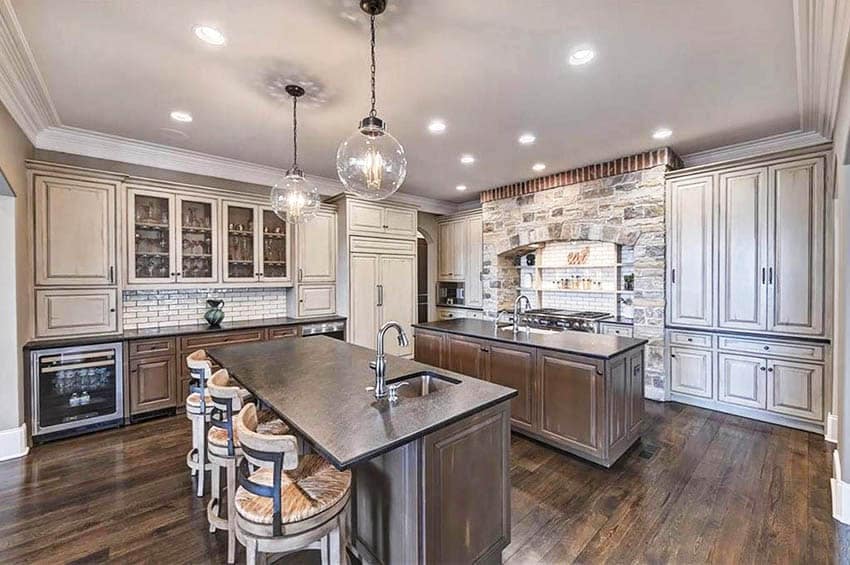 Kitchen with soapstone countertops, two islands, dark cabinets and distressed wood upper cabinets