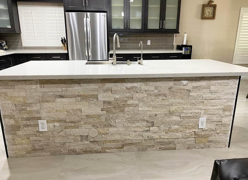 Kitchen with stacked stone island, countertop and dark cabinets