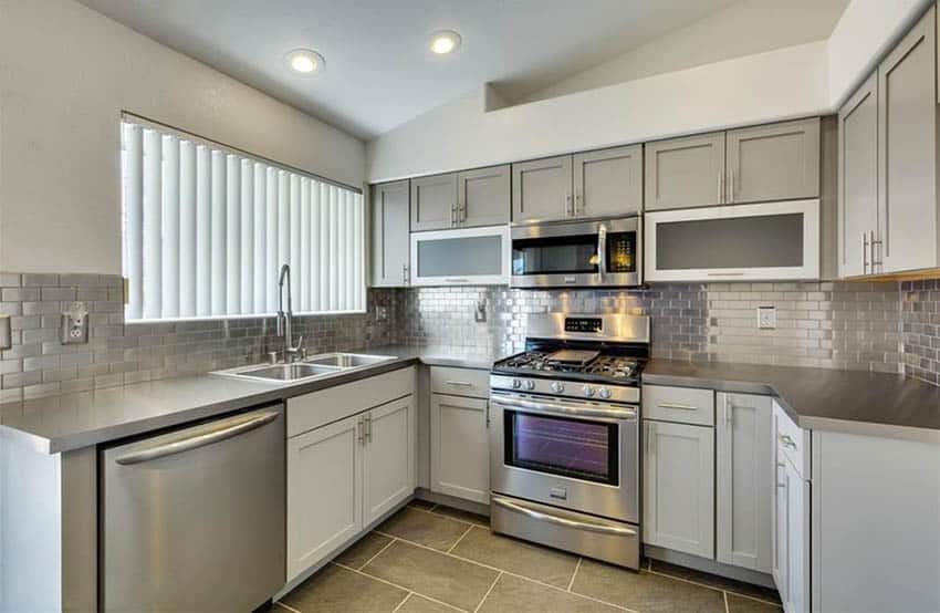 Kitchen with stainless steel countertops and backsplash with gray cabinets
