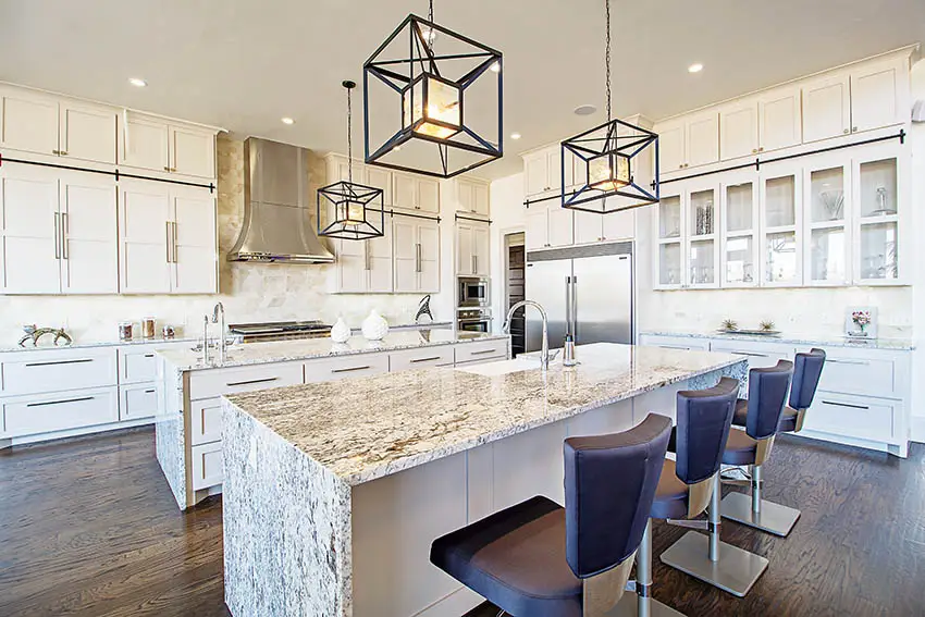 Kitchen with two islands with waterfall granite countertops white cabinets