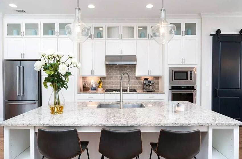 Kitchen with white granite countertops white cabinets and dine in island