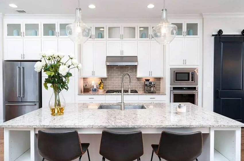 Kitchen with white granite countertops white shaker cabinets and dine in island