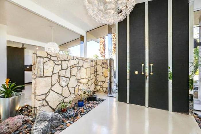Entryway with panel door, natural stone divider and pebble feature