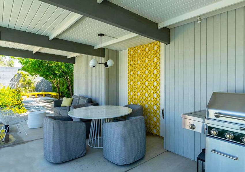 Outdoor area with shiplap walls, grilll and upholstered chairs