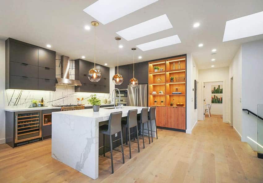 Modern kitchen with waterfall quartz countertop island dark cabinets three skylights