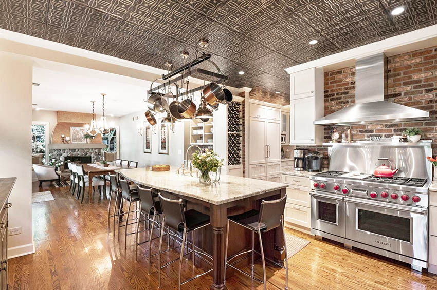 Open concept chefs kitchen with tin ceiling and brick walls