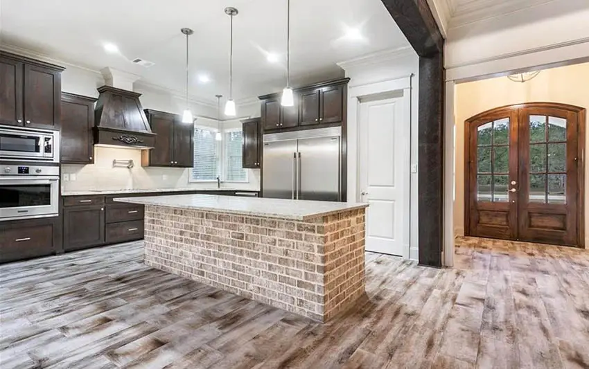 Open concept kitchen with brick island dark wood cabinets
