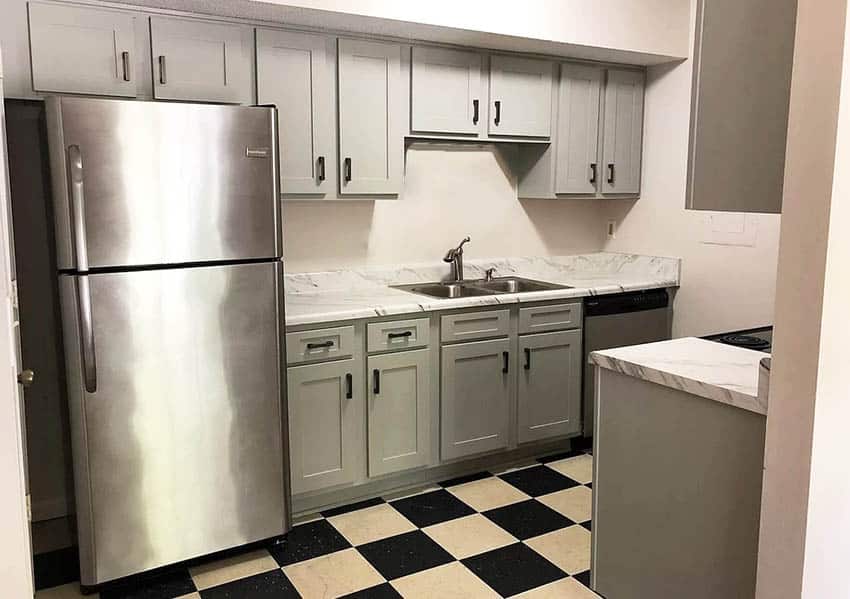 Small galley kitchen with cultured marble countertops, gray cabinets and black and white checkered flooring
