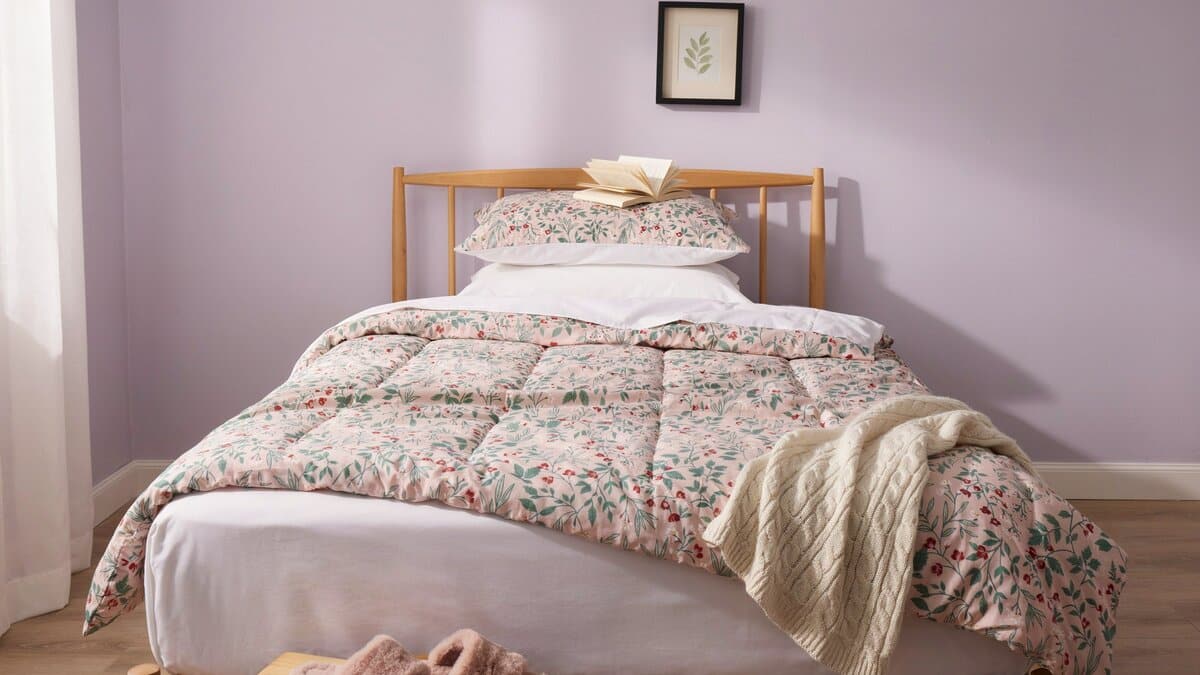 Floral quilt folded over white sheets on a wooden bed frame