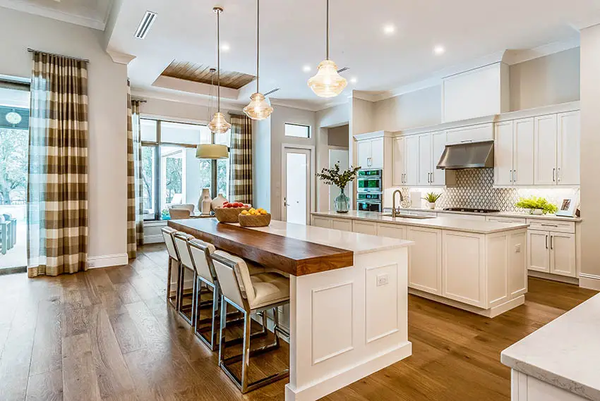 Traditional kitchen with two islands butcher block & quartz counters, white cabinets and wood flooring