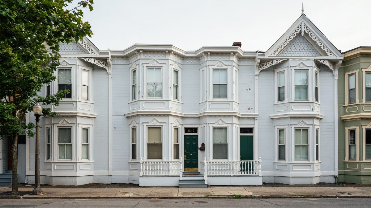 Pair of white Victorians with rounded double bay windows and dark green front doors
