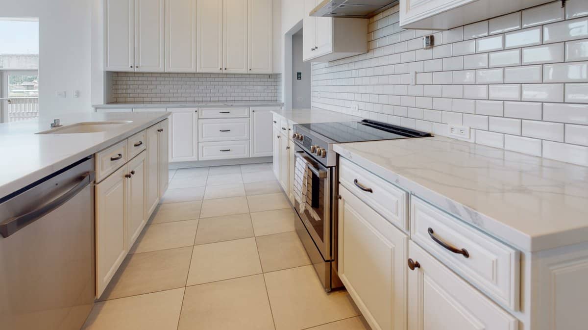 Transitional white kitchen with Calacatta quartz counters white subway tile and porcelain floor