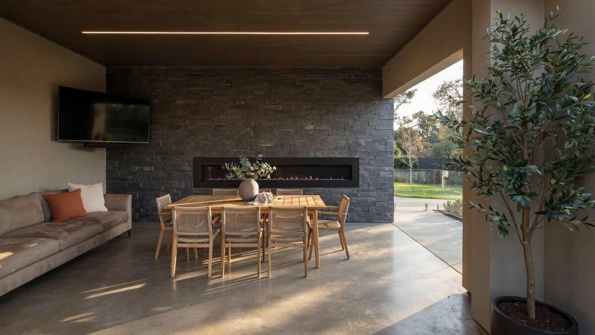 Covered patio with a teak dining table and TV above a fireplace
