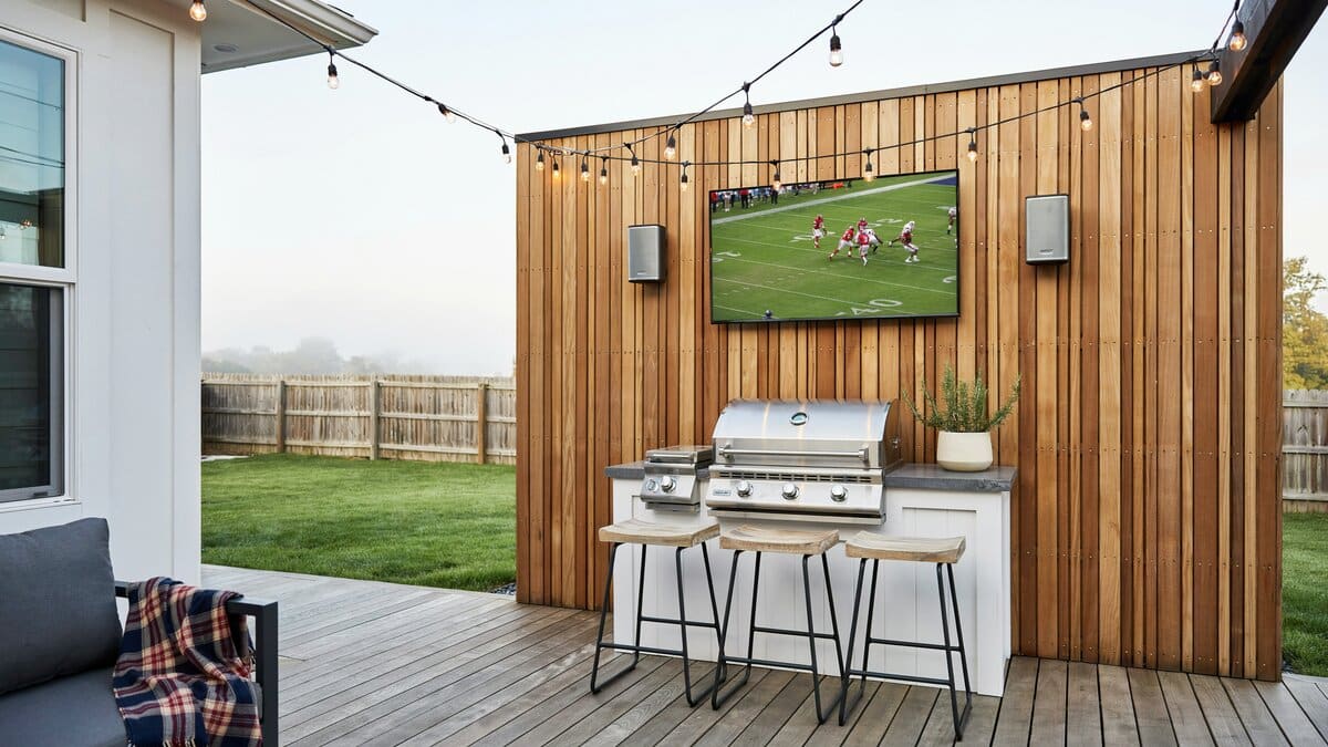 Backyard deck bar with a wall TV above a stainless barbecue grill