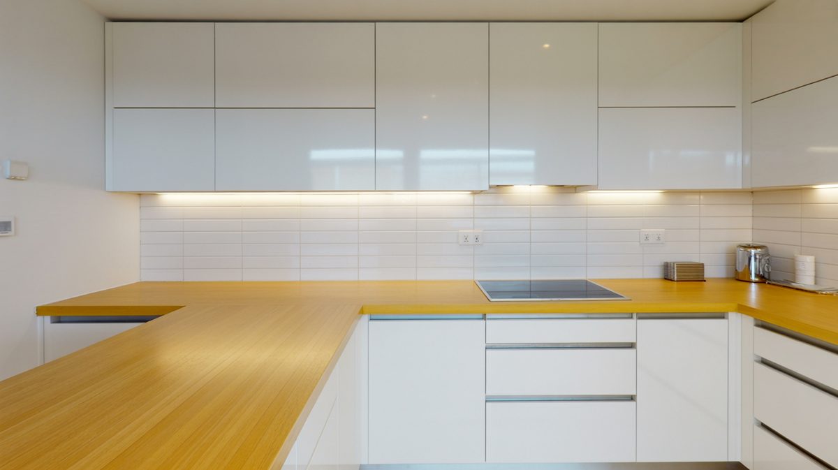Golden bamboo countertops running along sleek handleless white kitchen cabinets