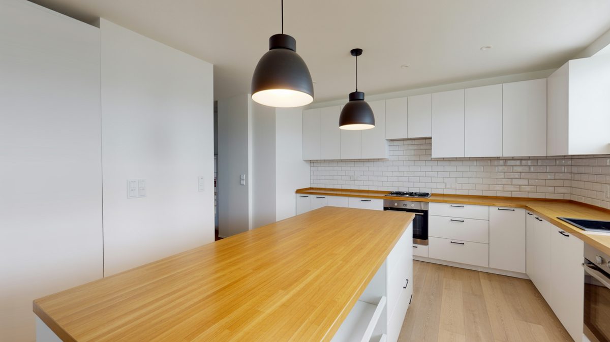 Bamboo island countertop with white cabinets, subway tile and black pendant lights