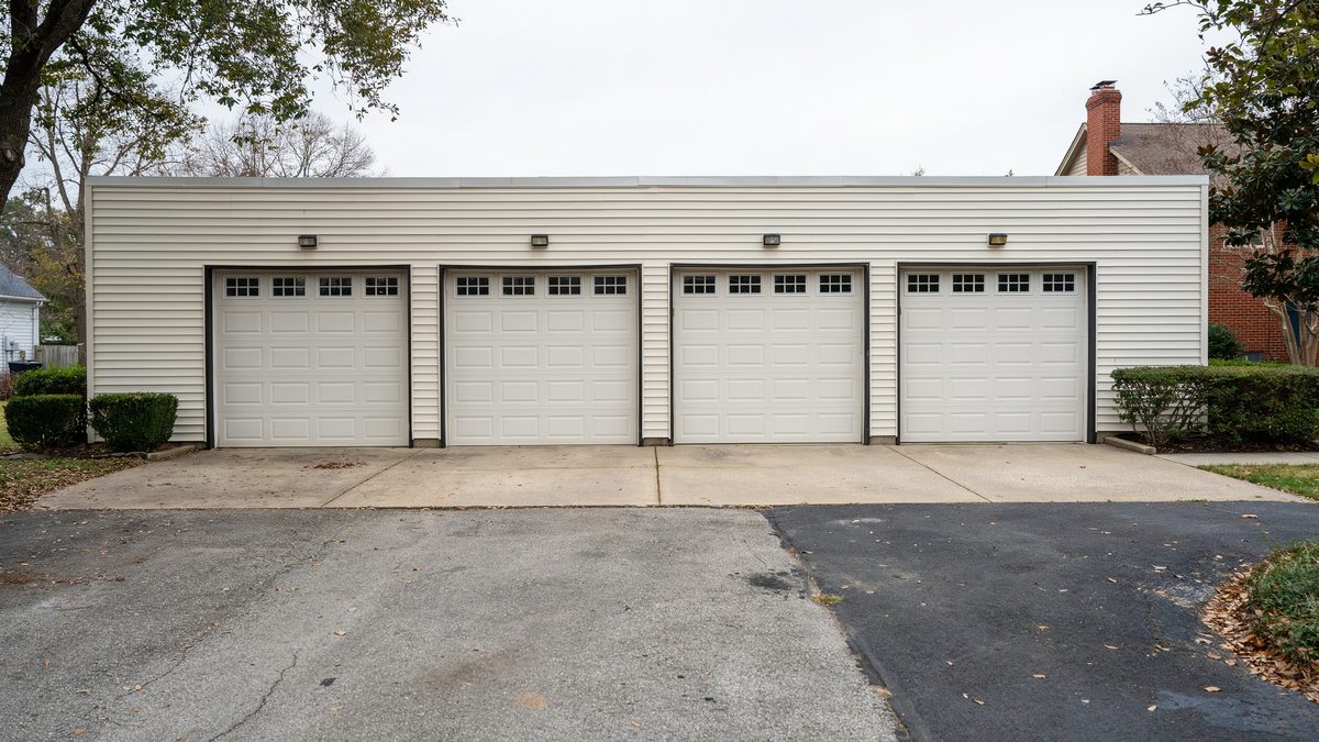Four side by side white doors on a long beige four car garage
