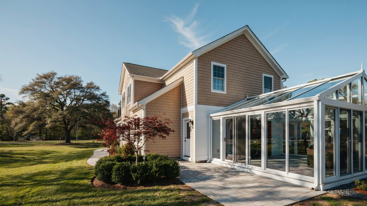 Prefabricated glass sunroom kit attached to a two story shingled house