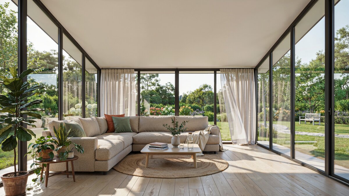 Bright sunroom featuring a large L shaped sectional couch beside floor to ceiling glass