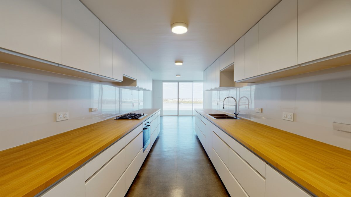 Galley kitchen with bamboo countertops, white cabinets and polished concrete floors
