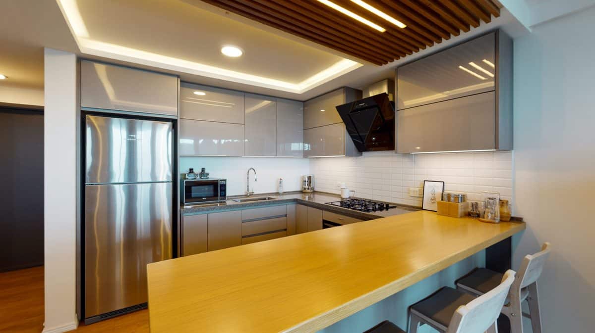 Gray gloss basement kitchenette with light bamboo breakfast bar and stainless refrigerator