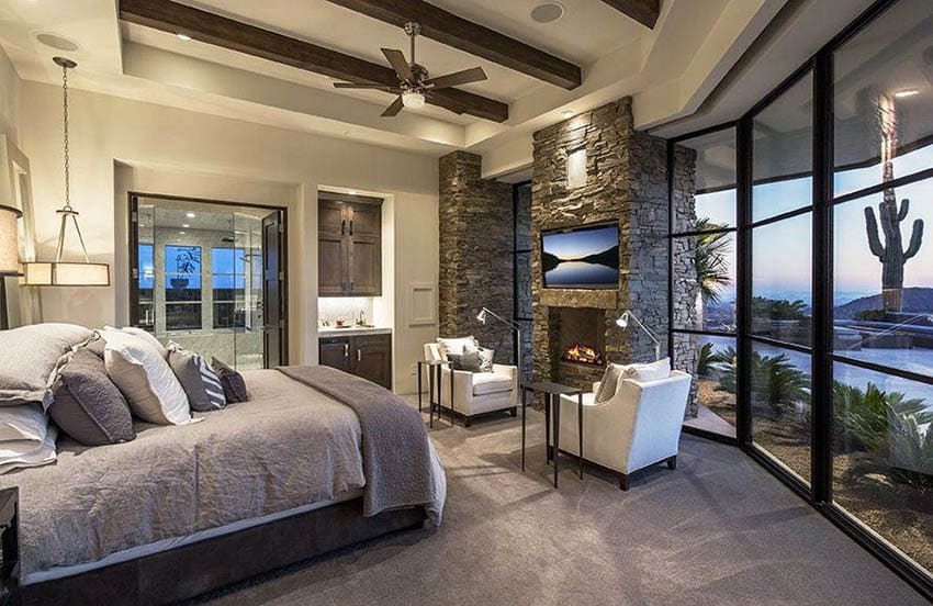 Contemporary bedroom with stone fireplace and sitting area