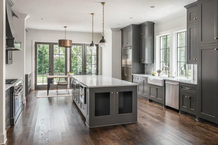 Contemporary kitchen with dark gray island and cabinets with white quartz counters pendant lights