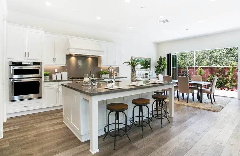 Contemporary kitchen with gray silestone countertops dining island white cabinets wood flooring