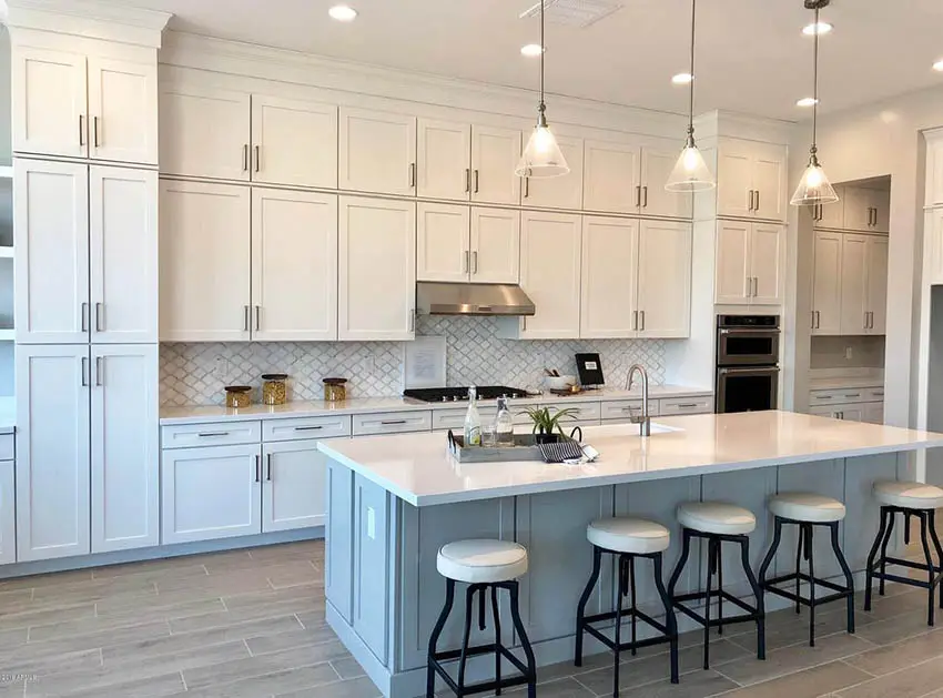 Kitchen with light gray island and white shaker cabinets