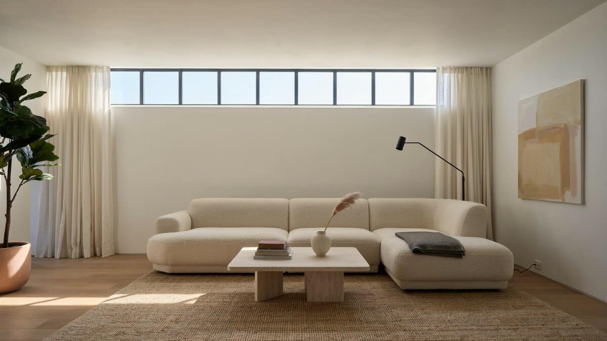 Cream sectional under a long clerestory window strip with sheer curtains