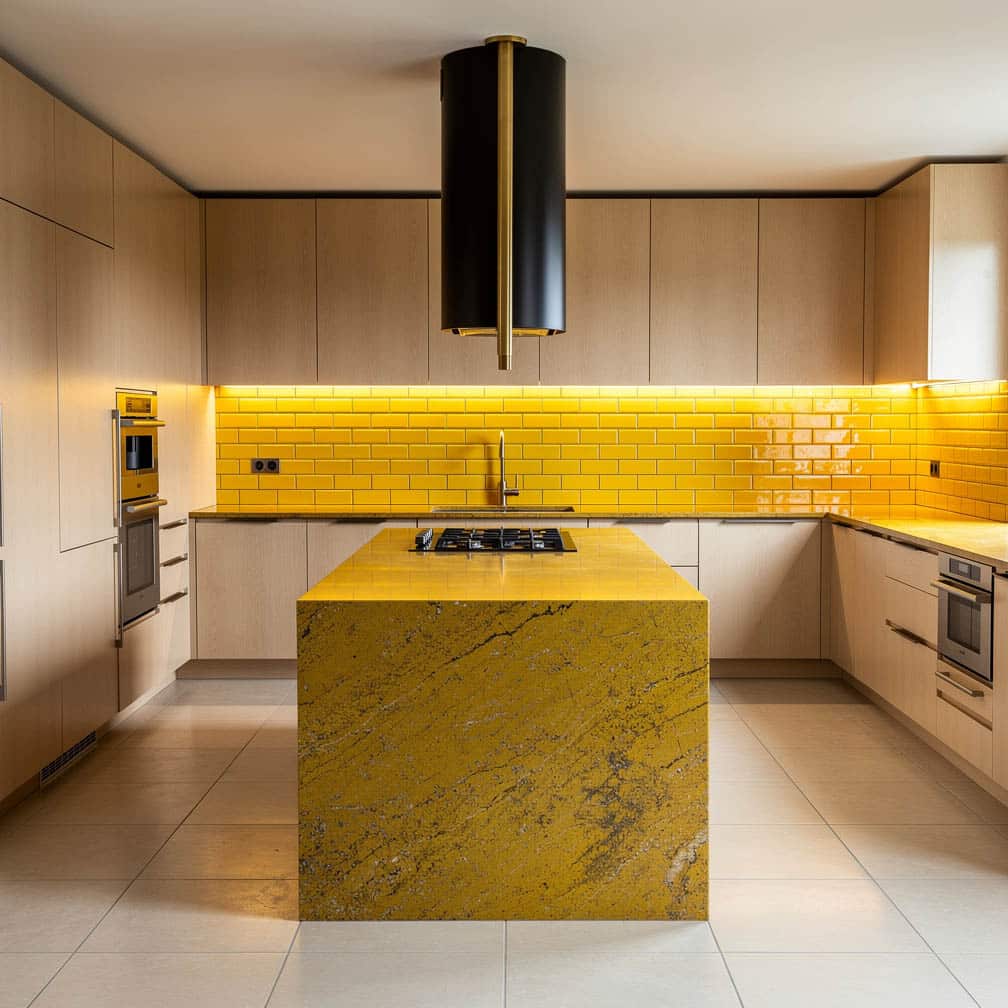 Cream maple flat-panel kitchen with bold yellow granite island and black cylindrical industrial range hood