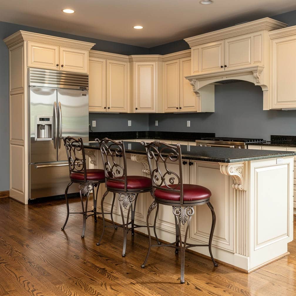 Cream raised panel kitchen with gray-blue walls, black granite peninsula and wrought iron barstools with red cushions
